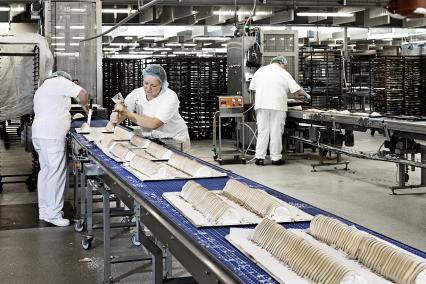 Et billede af mennesker og kager i en fabrikshal